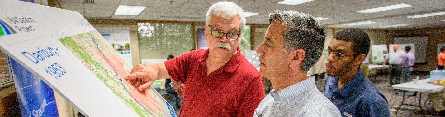 Photo of a man pointing at a historic Danbury map two men looking on