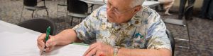 Photo of a man sitting at a table and writing